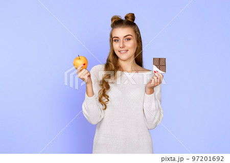 woman in sweater showing sweet chocolate bar and fresh apple 97201692