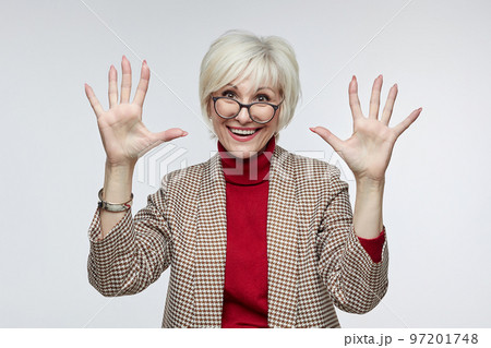 beautiful elderly woman with glasses holds her hands in front of her with open palms facing the camera. advertising concept of a business woman leader beautiful elderly woman with glasses holds her hands in front of her with open palms facing the camera. advertising concept of a business woman leader 97201748