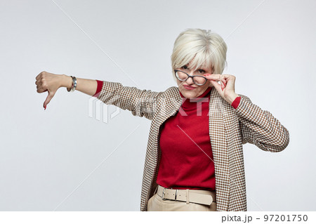 beautiful elderly woman with glasses gives a thumbs down. the concept of a business woman leader beautiful elderly woman with glasses gives a thumbs down. the concept of a business woman leader 97201750