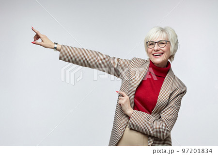 beautiful elderly woman with glasses points with her index finger at an empty seat. advertising concept of a business woman leader beautiful elderly woman with glasses points with her index finger at an empty seat. advertising concept of a business woman leader 97201834