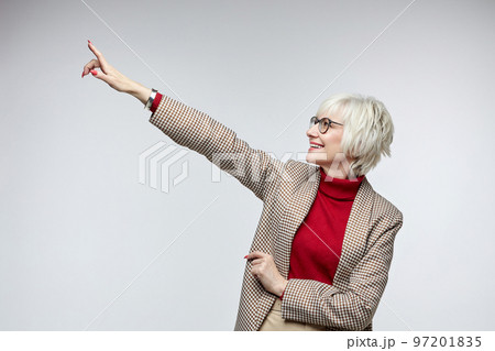 beautiful elderly woman with glasses points with her index finger at an empty seat. advertising concept of a business woman leader beautiful elderly woman with glasses points with her index finger at an empty seat. advertising concept of a business woman leader 97201835