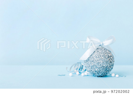 Christmas ball on colored background. decoration bauble with ribbon bow with copy space 97202002