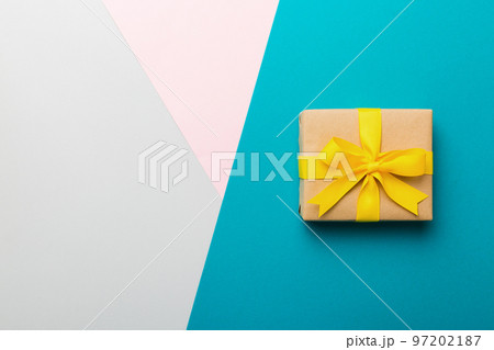 holiday paper present tied yellow ribbon bow top view with copy space. Flat lay holiday background. Birthday or christmas present. Christmas gift box concept with copy space holiday paper present tied yellow ribbon bow top view with copy space. Flat lay holiday background. Birthday or christmas present. Christmas gift box concept with copy space 97202187