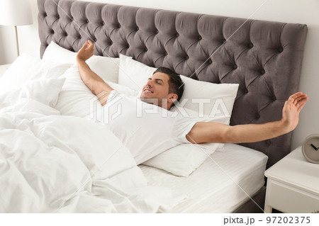 Man awakening on bed at home. Lazy morning 97202375