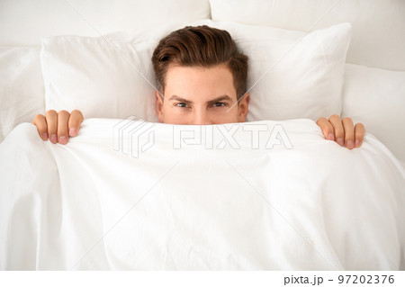 Man under blanket in bed at home, top view. Lazy morning 97202376