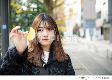 街中でイチョウを持つ女性 街中でイチョウを持つ女性 97203406