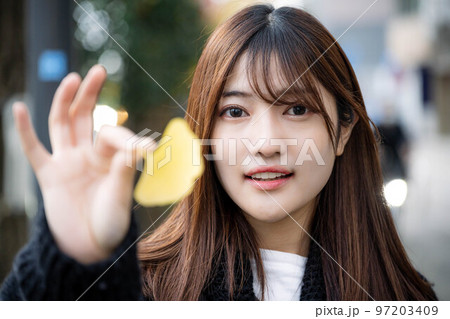 街中でイチョウを持つ女性 97203409