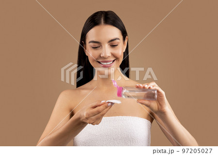 Smiling beautiful naked woman using micellar water and cotton pad 97205027