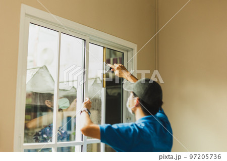 Worker use scraper cleaning window before installing tinting window film 97205736