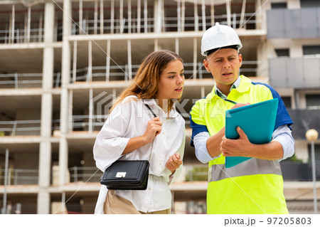 Builder talking with client at construction site 97205803