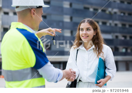 Engineer giving keys to apartment to woman 97205946