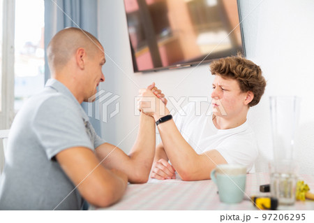 Happy smiling father and son arm wrestling at home 97206295