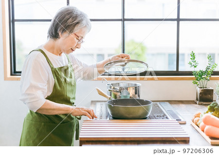 家のキッチンでIHクッキングヒーターを使って料理を作るアジア人の高齢者女性 家のキッチンでIHクッキングヒーターを使って料理を作るアジア人の高齢者女性 97206306