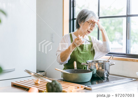 家のキッチンで料理を作るアジア人の高齢者女性（認知症・悩む） 97207003