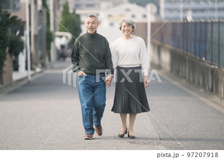 住宅街を歩く仲良しのシニア夫婦 97207918