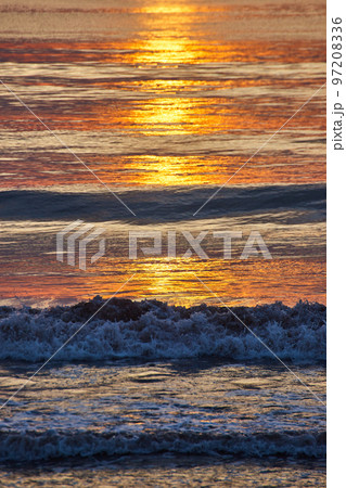 Detail vertical of crashing waves over east coast ocean with golden sunrise light casting light 97208336