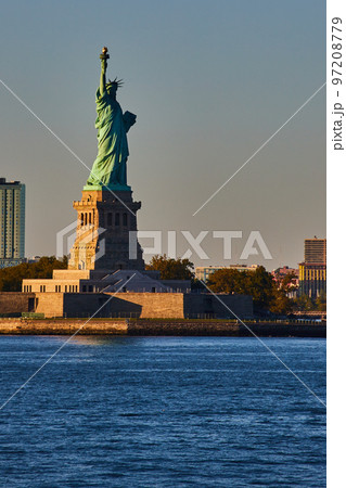 Light filling in half of Statue of Liberty in New York City from waters with golden hues 97208779