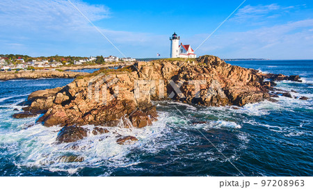Huge rocky island with lighthouse on Maine coast aerial with waves crashing over rocks Huge rocky island with lighthouse on Maine coast aerial with waves crashing over rocks 97208963