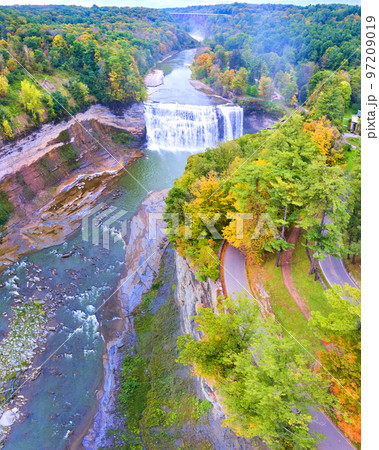 Aerial panorama over road along edge of cliffs with raging waterfall and bridge in background 97209019