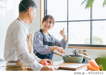 家のキッチンで一緒に料理・家事・自炊をする笑顔のアジア人高齢者男性と若い女性(家政婦・家事代行) 家のキッチンで一緒に料理・家事・自炊をする笑顔のアジア人高齢者男性と若い女性(家政婦・家事代行) 97210313