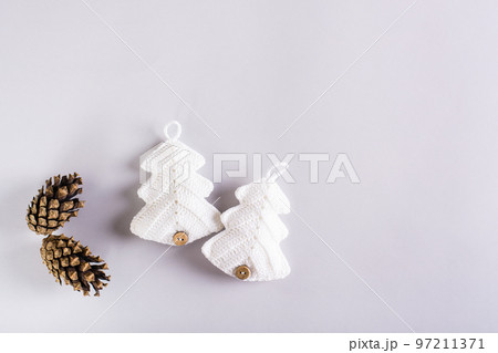 Two knitted fir trees and pine cones on a gray background. Handmade Christmas decor Two knitted fir trees and pine cones on a gray background. Handmade Christmas decor 97211371