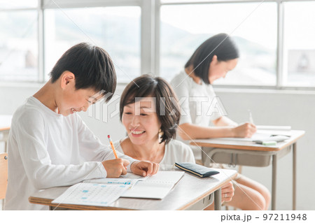 学校の教室・塾で先生と話す高学年のアジア人男子生徒（学習・教育） 97211948