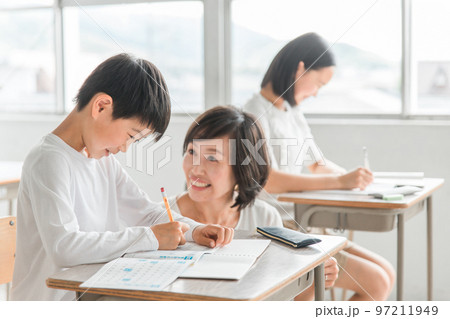 学校の教室・塾で先生と話す高学年のアジア人男子生徒（学習・教育） 97211949