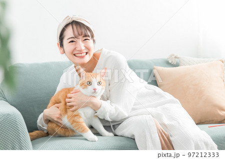 家のソファで猫を抱っこする飼い主のアジア人女性 97212333