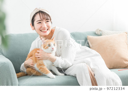 家のソファで猫を抱っこする飼い主のアジア人女性 97212334