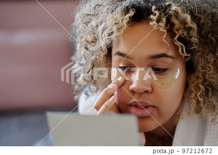 Close-up of young woman putting hydrating under eye patches 97212672