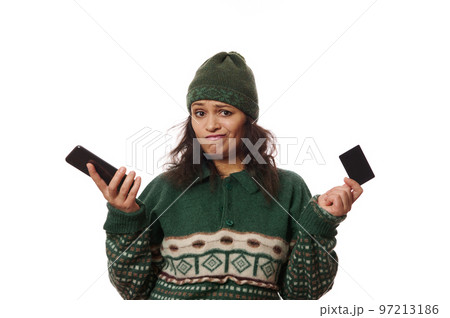 Frustrated brunette woman in warm wool clothes, holding her mobile phone, expresses disappointment due to a failed transaction or rejected payment, lack of cash on her credit card, on white background Frustrated brunette woman in warm wool clothes, holding her mobile phone, expresses disappointment due to a failed transaction or rejected payment, lack of cash on her credit card, on white background 97213186