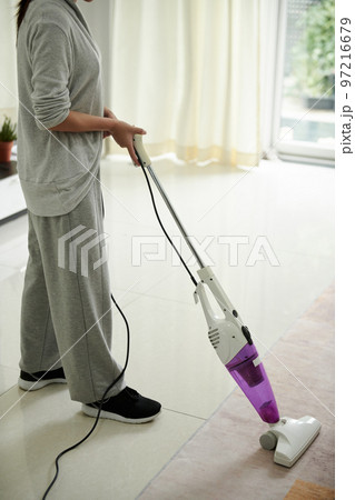 Cleaning lady vacuuming floor in house of client 97216679