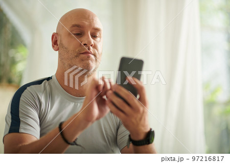 Mature man answering text message from friend or family member Mature man answering text message from friend or family member 97216817