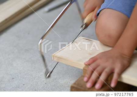 子供の夏休みの木工の宿題で糸鋸を使って切断 97217765