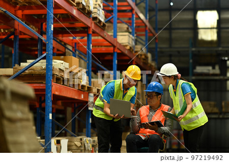 Middle age male manager and young workers using laptop with inventory checking software in retail warehouse 97219492