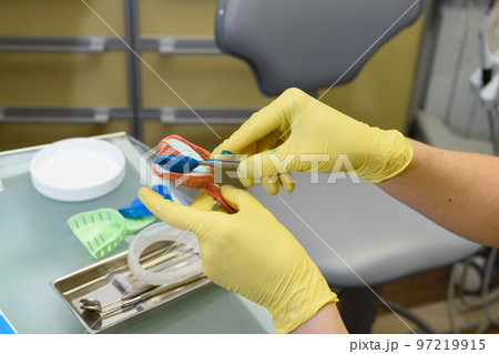 The orthodontist prepares a special paste for making an impression of the patient's teeth The orthodontist prepares a special paste for making an impression of the patient's teeth 97219915