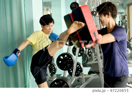 キックを打つ男性とミットを持つトレーナー 97220655