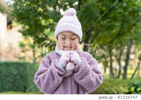 冬 ニット帽に手袋とマフラーをつける小学生の女の子の写真素材