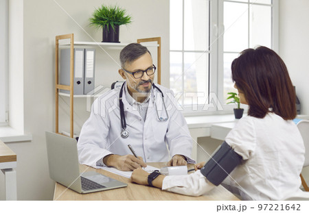 Smiling male doctor measuring pressure to female patient 97221642