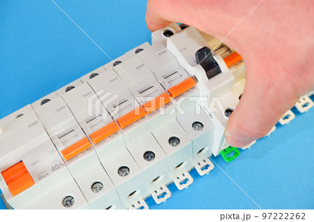Automatic differential current switch and circuit breakers on a blue background. A man's hand places an assault rifle of a different type and color in a row. Electrical engineering concept. 97222262