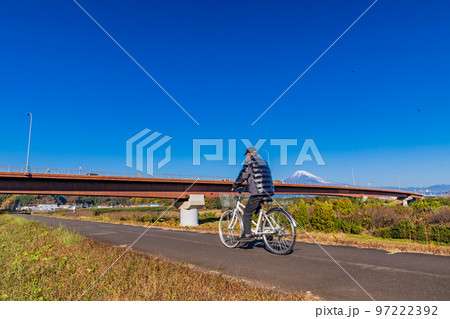 （静岡県）富士山の見える狩野川の土手をサイクリングする人 97222392