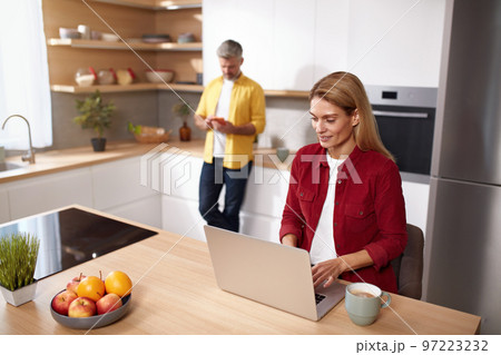 Blonde Woman Using Laptop At Kitchen. Happy Couple Spending Weekend Together 97223232