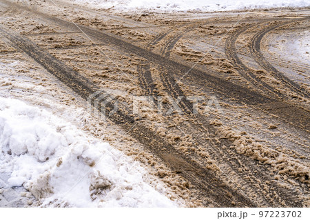 Winter road with car tracks in dirty snow and de-icing chemicals Winter road with car tracks in dirty snow and de-icing chemicals 97223702