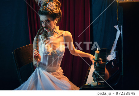 Magic. Portrait of mysterious young lady, medieval person in elegant white dress sitting at the piano and performing. Comparison of eras, beauty, history, art 97223948