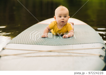 The child lies floating on the water on a large sup board. Water sports 97224220