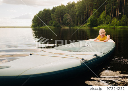 The child lies floating on the water on a large sup board. Water sports 97224222