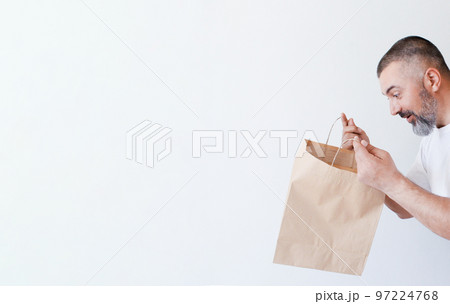 Surprised bearded man looks in paper bag 97224768
