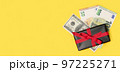 black gift box with a cash money on a yellow background. Holiday background 97225271