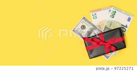black gift box with a cash money on a yellow background. Holiday background 97225271