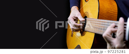 Guitarist playing acoustic guitar on black background, selective focus. 97225281